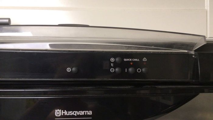 En person pekar på en snabbkylknapp på en Husqvarna ugnspanel med kontrollknappar och en digital display.