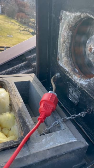 Snurrande maskindel synlig genom inspektionslucka på utrustning, med frostliknande mönster och röd kontakt i förgrunden.