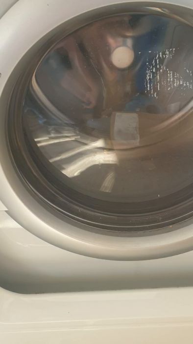 Det är en suddig film av en tvättmaskin i drift med kläder synliga genom den runda glasluckan.