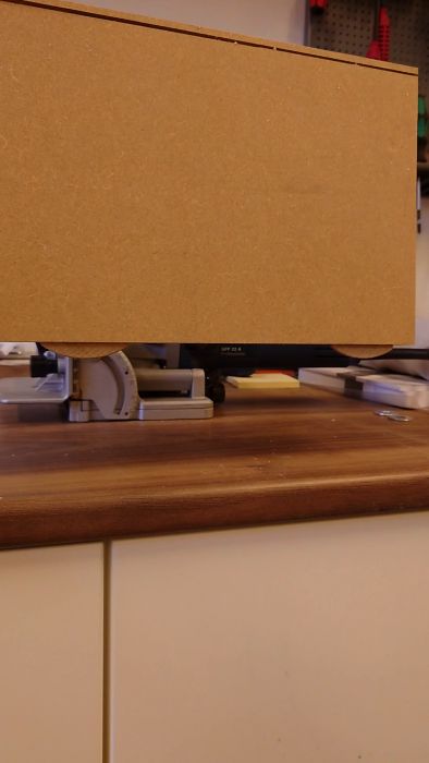 En elektrisk häftpistol frän Bosch på ett arbetsbord med MDF-skiva framför. Arbetsmiljö, troligtvis för något bygg- eller hantverksprojekt.