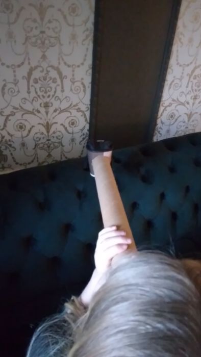 En handskklädd hand på en kartongarm hålls upp av en person som inte syns helt i filmen.