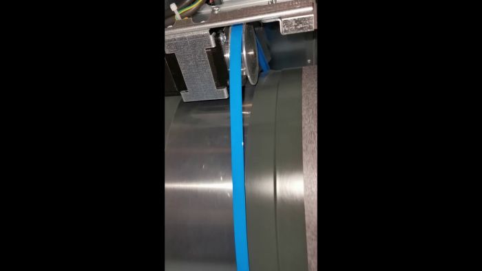 Maskinbearbetning i arbete med en smal blå plastbit som formas eller skärs av en roterande anordning.