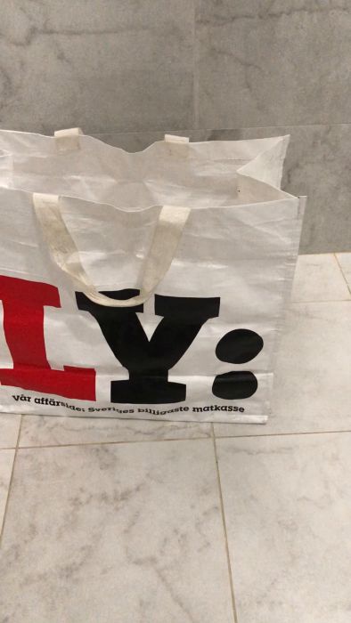 Det är en film av en transparent papperskorg med ett rosa föremål inuti, troligen ett blommblad, nära en svart yta, möjligen en hylla eller bord.