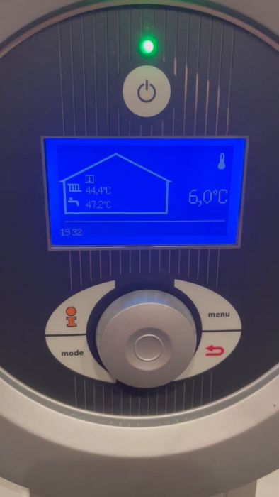 Digital display av uppvärmningssystem visar temperaturinställningar och status, med knappar för navigering runtomkring. En grön indikatorlampa är tänd.