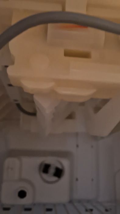 Inuti en suddig diskmaskin; roterande sprutarmar, vatteninlopp och skenor syns.