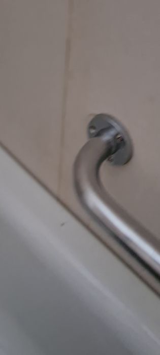 En närbild på en metallhandtag monterad på en vit yta, möjligen en dörr eller ett skåp.