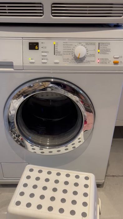 En suddig film av en vit tvättmaskin med upplyst kontrollpanel och till synes igång.