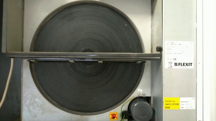 Ett industriellt ventilationsaggregat med en stor rund fläkt och underhållsetiketter, inklusive CE-märkning och serienummer.