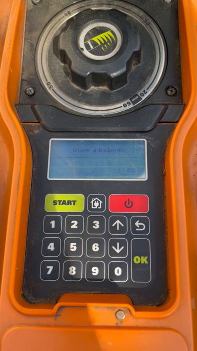 En orange och svart apparat med knappsats, startknapp och display som visar texten "Utom arbetstid!"