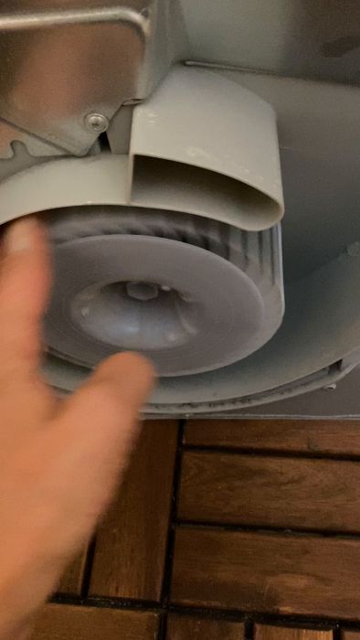 En oskarp film av en hand nära en toalettpappersdispenser, med toalettpapperet som rullar ut.