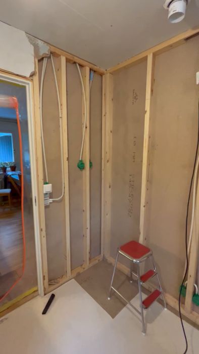 En suddig interiörbild av en pågående renovering med exponerade träreglar och olika verktyg och byggmaterial i förgrunden.