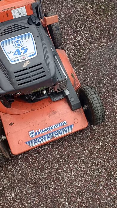 Det är en film av en orange och svart gräsklippare från Husqvarna, modell Royal 48S, på en grusväg.