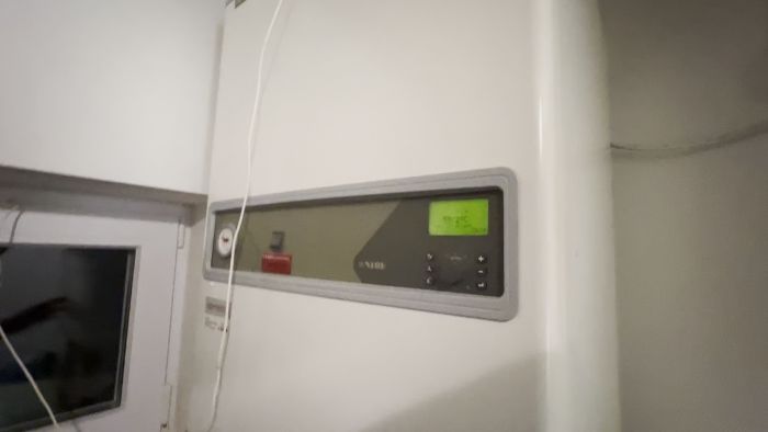 Det är ett värmepumps styrenhet från NIBE med en LCD-display som visar 52.2°C, omgiven av en vit ram och knappar.