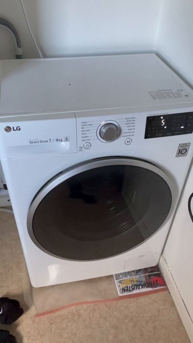En vit LG tvättmaskin i funktion, digital display visar inställningar, ligger i ett ljust rum.