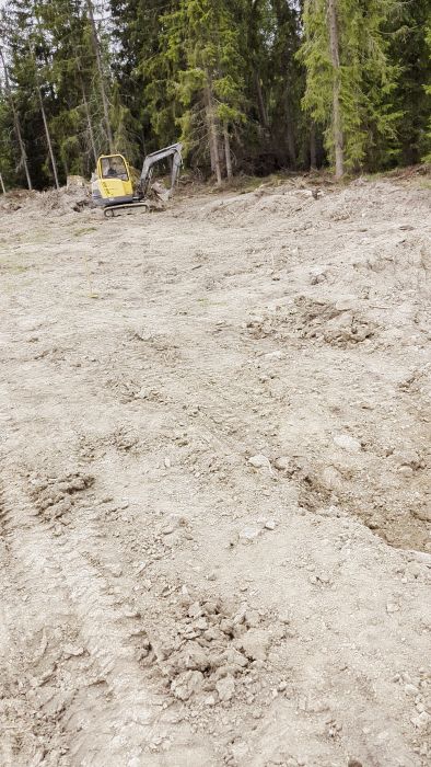 Filmen visar en närbild av grov, ojämn grusig mark, möjligen en byggarbetsplats eller utgrävningsområde med synliga stenar och jord.