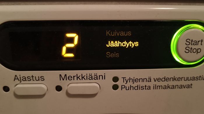 Panel av en torktumlare med inställningar, start/stopp-knapp belyst i grönt och text på finska indikerar "Jäähdytys" (kylning) fas.