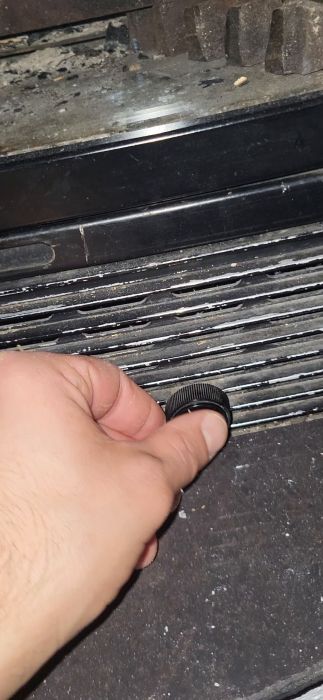 En hand som håller ett svart objekt nära smutsiga ventilationsgaller på en elektronisk enhet.