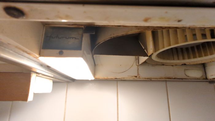 Ett gammalt, smutsigt takmonterat ventilationssystem med synlig fläkt och damm.