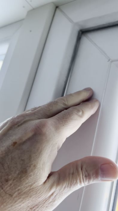 En person håller på att öppna eller stänga en vit dörr med sin hand.