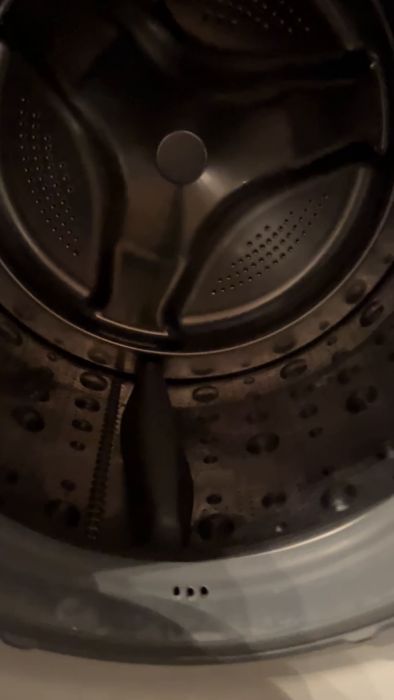 Inuti en snurrande tvättmaskins trumma, suddig genom rörelse med synlig lucka och kontrollknappar.