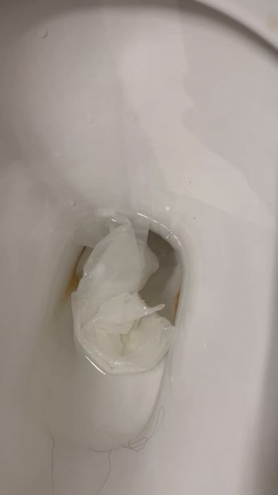 En toalettstol med plastpåse och vätska i skålen, indikerar eventuellt en tätning eller blockering.