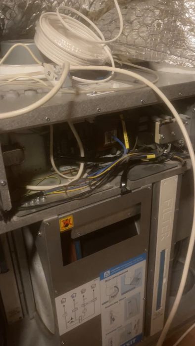 Det här är en suddig film av elektrisk utrustning, med kablar och en varningsskylt för elektricitet, möjligen inne i en server eller ett elskåp.