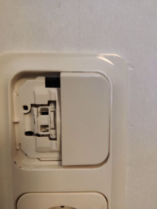 Filmen är suddig och visar en närbild av ett finger som verkar trycka mot en vit plastdel, möjligtvis en strömbrytare eller apparat.