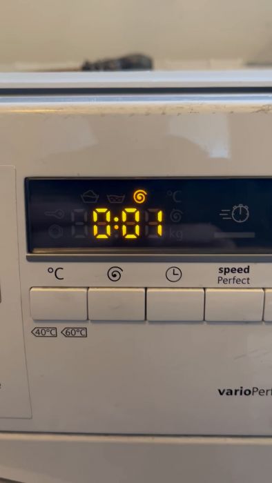 En film av en tvättmaskins display visar tiden 0:01 med symboler för avslutad tvättcykel.