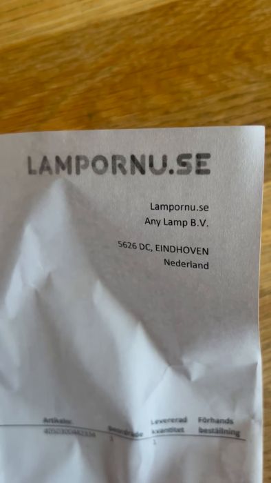 En hand håller ett skrynkligt dokument med texten "LAMPORNU.SE", någon adress i Nederländerna, och delar av en orderlista.