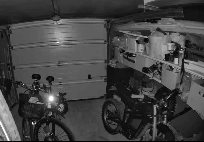 Videoklipp som visar interiören av ett garage filmat med en säkerhetskamera. I klippet syns cyklar och hyllor med förvaringslådor och verktyg. Ett ljusfenomen kan också ses i film.