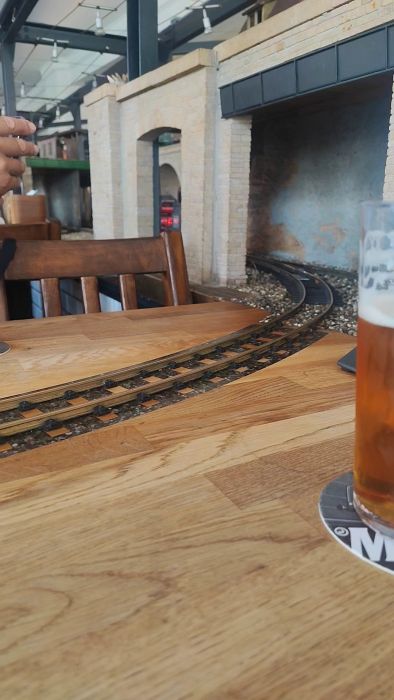 En modelljärnväg används för att servera öl i en intressant restaurangmiljö. Kolla in när tåget levererar drycken precis till bordet.