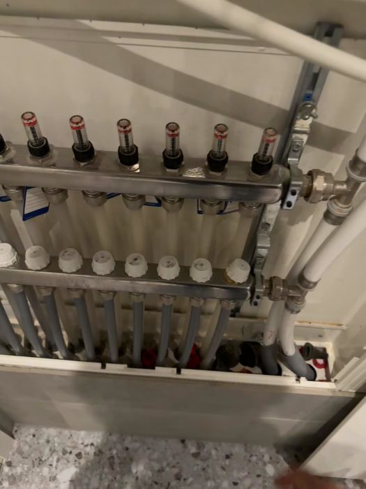 En användare demonstrerar hur flödesmätarna i ett golvvärmesystem inte rör sig, oavsett om reglagen stängs eller öppnas. Flödesmätarna står stilla högst upp och fungerar inte som förväntat. Filmen visar en genomgång av systemet som inte beter sig korrekt.