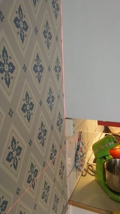 Upptäck hur en lasernivå används för att få raka linjer i hörn vid tapetsering eller målning. Videon visar ett hörn längst åt höger i ett rum där lasern projicerar en exakt linje. Perfekt för DIY-renoveringar och att säkerställa precision i byggprojekt.