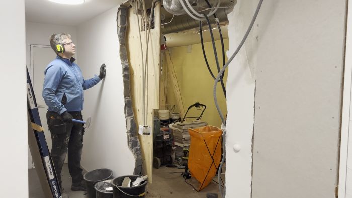 Följ med när vi river en vägg i förrådet för ett mer öppet utrymme. Borttagning av ventilationsrör och annan utrustning dokumenteras. Trots rörigt arbete med slägga och tigersåg når vi framsteg. Målet är att få ned hela väggen innan dagens slut.