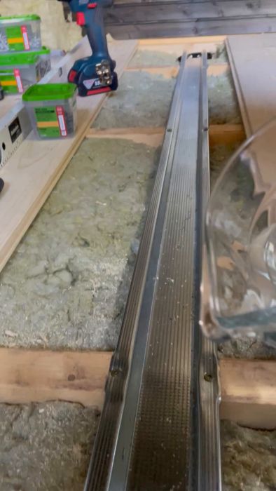 Titta när ett bastugolv får sin sluttande ränna för vattenavledning. Golvet är nästan klart och byggherren funderar på bästa behandling, antingen enbart olja eller med färgpigment. Bastuaggregatet är också redo för installation. Se byggprocessen fortskrida!