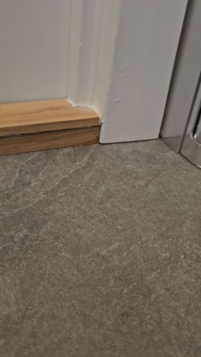 En video som visar potentiella problem med vattenskydd vid duschtröskeln efter en total renovering. Diskuterar avsaknaden av silikon och fog, samt oro för vattenläckage och behovet av en oberoende besiktningsman.