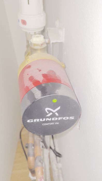 En Grundfos Comfort PM cirkulationspump från ett inlägg där användaren berättar att pumpen låter konstigt efter att värmesystemet varit avstängt i två månader. Pumpen har varit igång i 3-4 veckor efter återstart och orsaken till ljudet diskuteras.