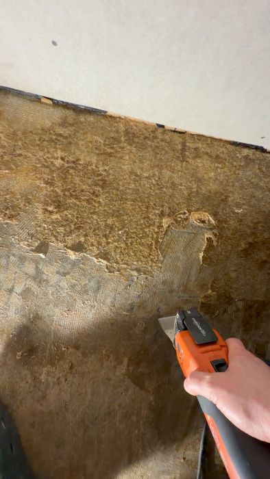 Se hur luddet på den gamla mattan avlägsnas med vatten och en Fein. Ett praktiskt tillvägagångssätt där försiktighet kring eventuell asbest hanteras med pannben och knäarbete.