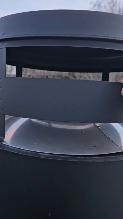 Video som visar tveksam montering av skorstenen NVI 2000 Combi. Regnskyddet sitter löst och installationen verkar sakna ordentligt intag för tilluft. Frågorna rör säkerhetsrisker såsom buller och risk för vatteninträngning vid kraftig blåst och regn.