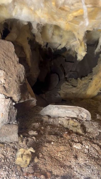Filmen visar ett problem med isolering under ett brädgolv där tidigare plast och isolering fallit ner. Diskussionen handlar om huruvida man bör åtgärda detta genom att isolera underifrån och lägga åldersbeständig plast på marken.